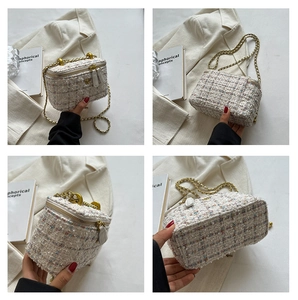 Dettagli di una borsa a tracolla in tweed con catena dorata e decoro floreale