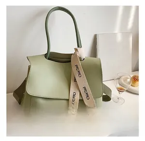 Détail du sac à main en cuir vert avec ruban décoratif et large bandoulière réglable
