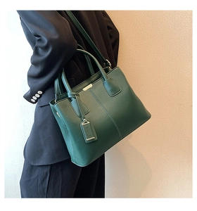 Detail of dark green pebble leather tote bag with metallic buckle and shoulder strap