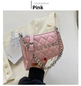 Detail of pink quilted crossbody bag with silver chain and metal heart ornament