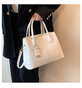 Detail of beige lychee pattern handbag featuring gold hardware and removable shoulder strap