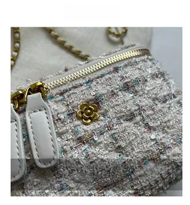 Dettaglio del tessuto in tweed e fibbia in metallo a camelia dorata su borsa a catena