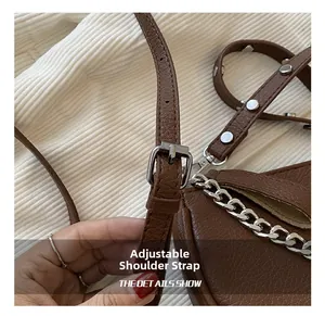 Detail of adjustable shoulder strap with silver buckle on brown lychee leather bag