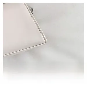 Macro shot of white leather handbag showing premium stitching and textured fabric details