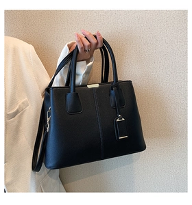 Detail of black lychee grain leather tote bag with gold hardware and shoulder strap