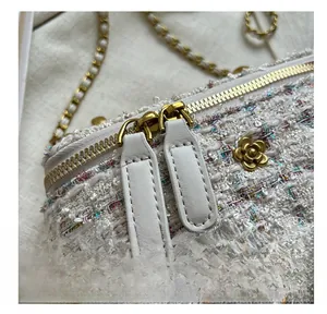 Dettaglio della doppia cerniera e dell'ornamento di camelia dorata su borsa in tweed
