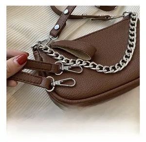 Detail of detachable silver metal chain and lobster clasp on brown pebbled leather bag