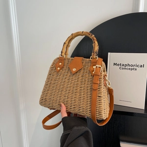 Trapezoidal woven straw handbag with bamboo top handle and brown leather shoulder strap
