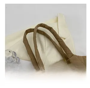 Detail of brown quilted tote bag showing sturdy double handles and diamond stitching