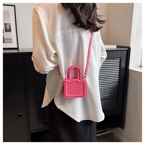Mini sac à main rose vif porté en bandoulière par un mannequin vue de dos élégante
