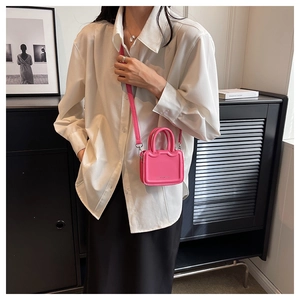 Gros plan d'un sac bandoulière en cuir rose sur modèle avec détails gaufrés délicats