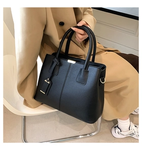 Close-up of black lychee textured handbag with gold hardware on a lifestyle setting
