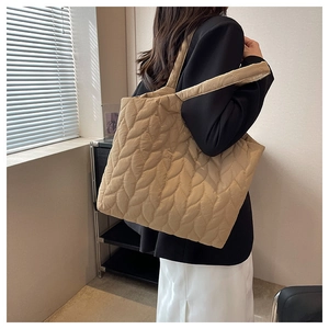 Detail of leaf-patterned quilted stitching on a large khaki tote bag with wide straps