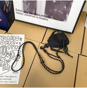 Détail d'une mini pochette en nylon noir avec cordon tressé à pois noirs et blancs