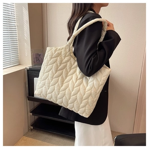 Close-up of beige quilted tote bag with leaf pattern and wide shoulder strap
