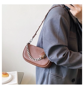 Close-up of brown textured leather underarm bag with silver chain and rivet strap