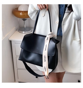 Détail du sac bandoulière en similicuir noir avec ruban décoratif à imprimé lettres bicolore