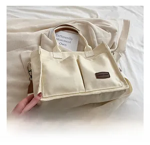 Close-up of minimalist canvas tote with front pockets and adjustable shoulder strap