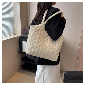 Detailed view of white quilted tote bag with leaf pattern stitching on soft material