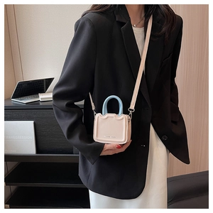 Détail du mini sac rose avec poignée bleue et bord ondulé dans un décor de bureau chic