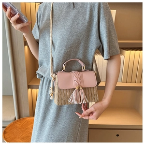 Détail du sac besace en paille avec rabat en cuir rose et pompons décoratifs