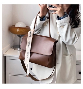 Vue détaillée d'un sac à bandoulière en cuir marron avec un ruban décoratif sur la poignée