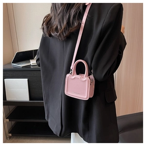 Mini sac bandoulière rose à bords ondulés avec logo porté par un mannequin