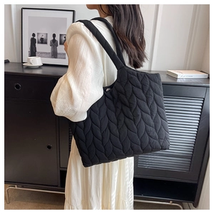 Black quilted tote bag with wavy puffer texture shown on model for daily commuting