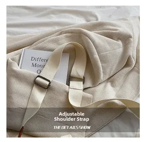 Detail of off-white corduroy tote bag showing adjustable wide strap and metal buckle