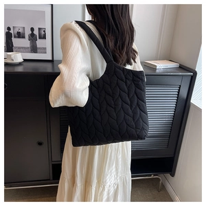 Detail of black quilted tote bag with unique leaf-textured fabric and wide shoulder strap