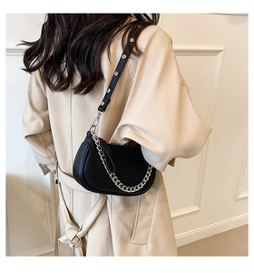 Detail of black pebbled leather half-moon bag with silver rivets and chunky chain strap
