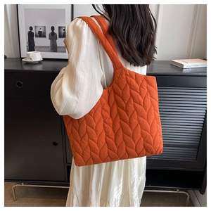 Close-up of orange quilted nylon tote bag featuring leaf pattern stitching detail