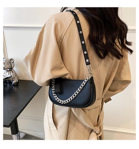 Detail shot of black pebbled leather half-moon bag with silver studs and chain straps