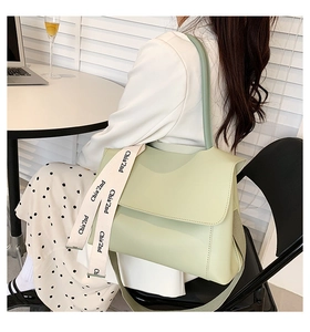 Détail d'un sac cabas en cuir vert sauge avec bandoulière élégante à lettrage