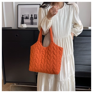 Quilted orange tote bag details with leaf pattern texture on white dress model