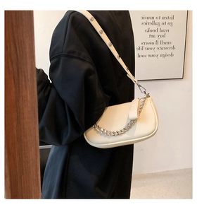 Detail of cream vintage underarm bag featuring silver chain and studded leather strap