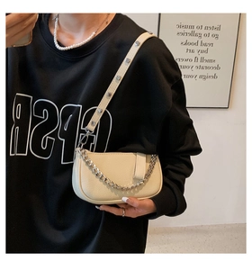 Detail of off-white textured underarm bag with silver chain and rivet leather strap