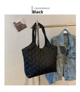 Detail view of black quilted nylon tote bag with unique wave pattern on display