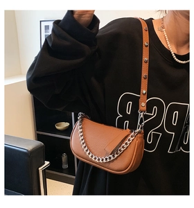 Close-up of brown crescent bag with silver chain and rivet details on the strap
