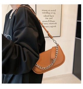 Close-up of caramel leather shoulder bag with vintage silver chain and lychee texture