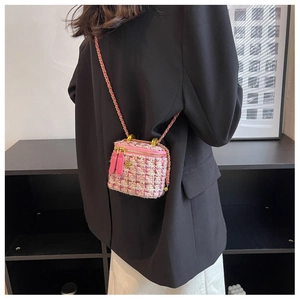 Dettaglio borsa a tracolla in tweed rosa con ciondolo a camelia dorata e catena