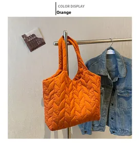 Detail of orange quilted tote bag showing leaf-pattern stitching and glossy nylon texture