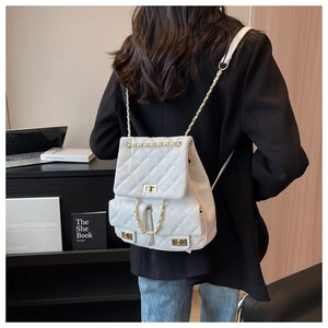 White quilted backpack with gold chain straps and turn-lock pockets shown on a model