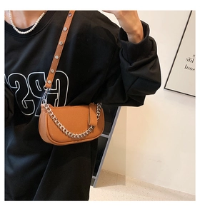 Detailed close-up of brown crescent bag with silver chain and rivet shoulder strap