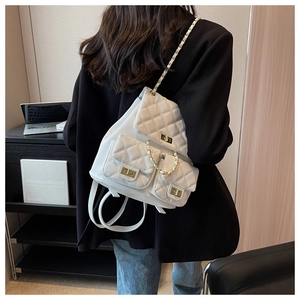 White quilted backpack with gold chain straps and three outer pockets shown in lifestyle setting