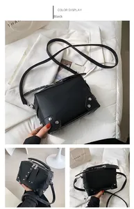 Detail view of black square crossbody bag with silver rivet studs and dual zippers