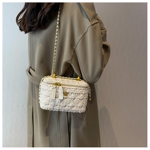Dettaglio borsa a tracolla in tweed bianco con fibbia a fiore dorato e catena su cappotto