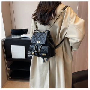 Detail of black quilted leather backpack with gold chain straps and metal twist lock