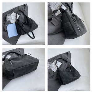 Detail of dark gray matte tote bag showing side metal zippers and adjustable strap