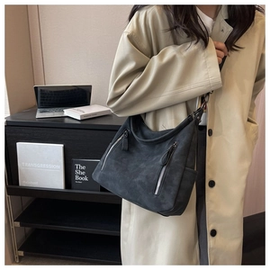 Gray suede hobo bag with dual zipper pockets shown being worn with a khaki coat